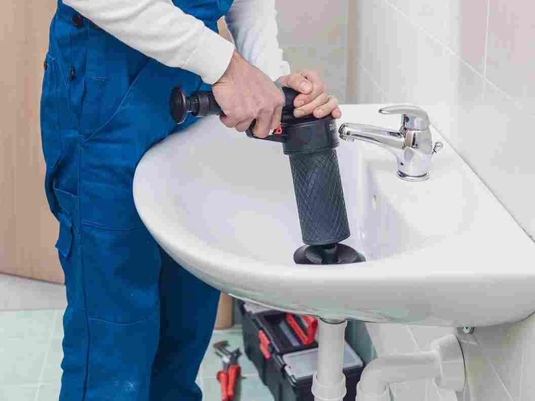 Plumber clearing a clogged sink drain