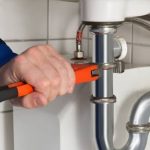 Professional plumber repairing a common residential plumbing issue under a kitchen sink | Common Plumbing Issues