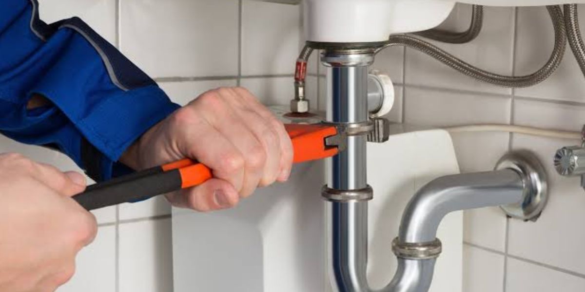 Professional plumber repairing a common residential plumbing issue under a kitchen sink | Common Plumbing Issues